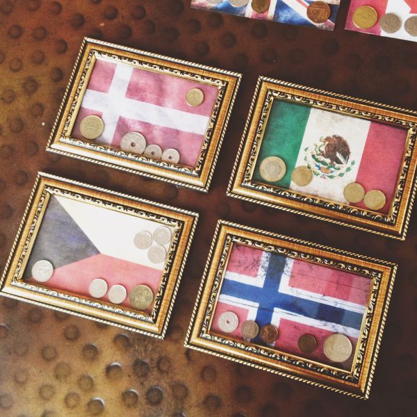 four framed pictures with different flags and coins in them on top of a wooden table