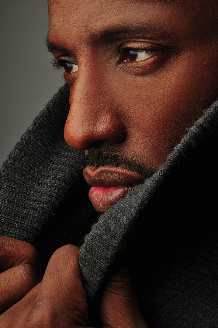 a close up of a person holding a cell phone to his ear and wearing a sweater