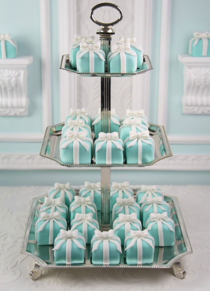 two tiered trays with blue and white decorated cookies on them, each holding a bow