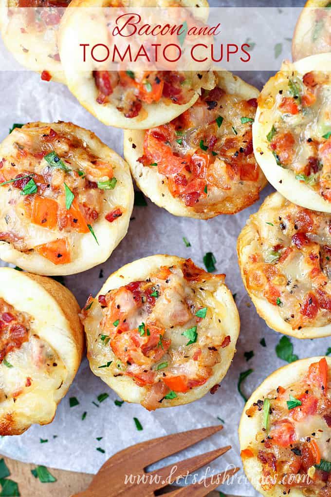 bacon and tomato mini pizzas on a sheet of parchment paper with utensils