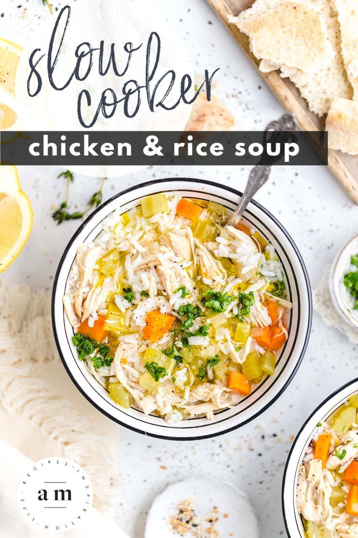 two bowls filled with chicken and rice soup on top of a white table next to sliced lemons