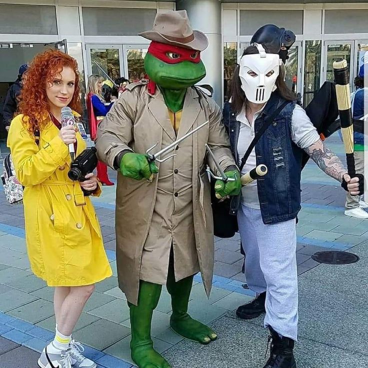 three people dressed up in costumes standing on the sidewalk with one person wearing a mask