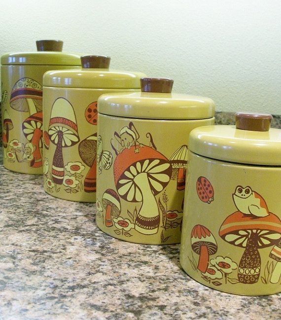 four yellow canisters are lined up on the kitchen counter with mushrooms painted on them