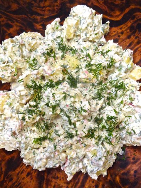 a wooden table topped with a salad covered in cheese and dill sprinkles