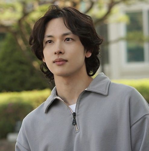 a young man in a gray jacket standing outside