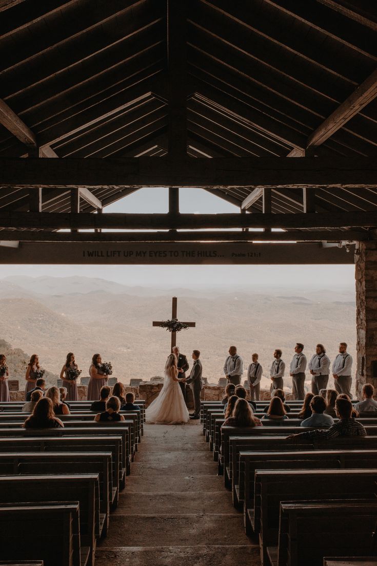 a group of people standing in front of pews at a church with a cross