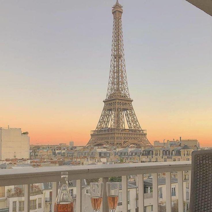 the eiffel tower towering over paris is seen from an apartment balcony at sunset