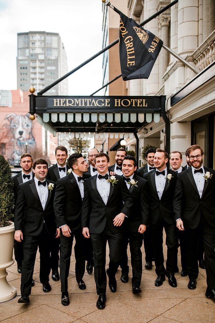 a group of men standing next to each other in front of a hotel sign and building