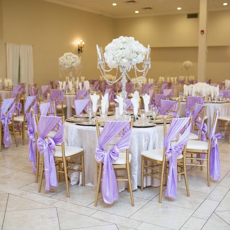 the tables are set up with purple sashes and white flowers in centerpieces