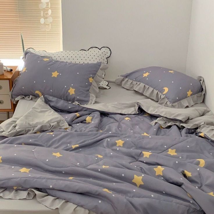 a bed with grey and yellow stars on the comforter, pillows and pillow cases