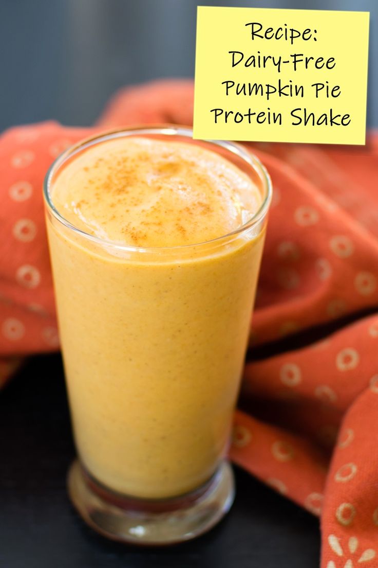 a glass filled with pumpkin pie protein shake on top of a red cloth covered table