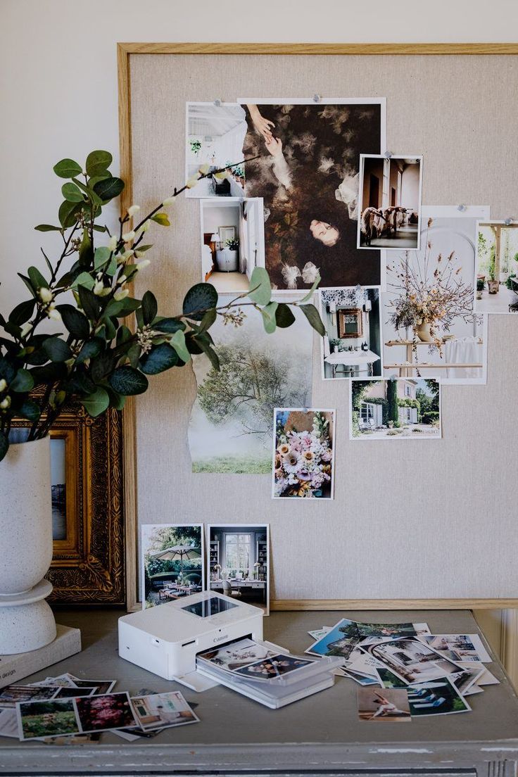 a table topped with pictures and plants next to a vase filled with flowers on top of it