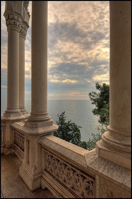 an outdoor area with columns and pillars overlooking the ocean