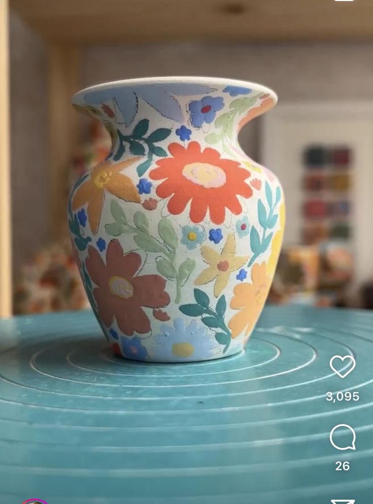 a colorful vase sitting on top of a blue table