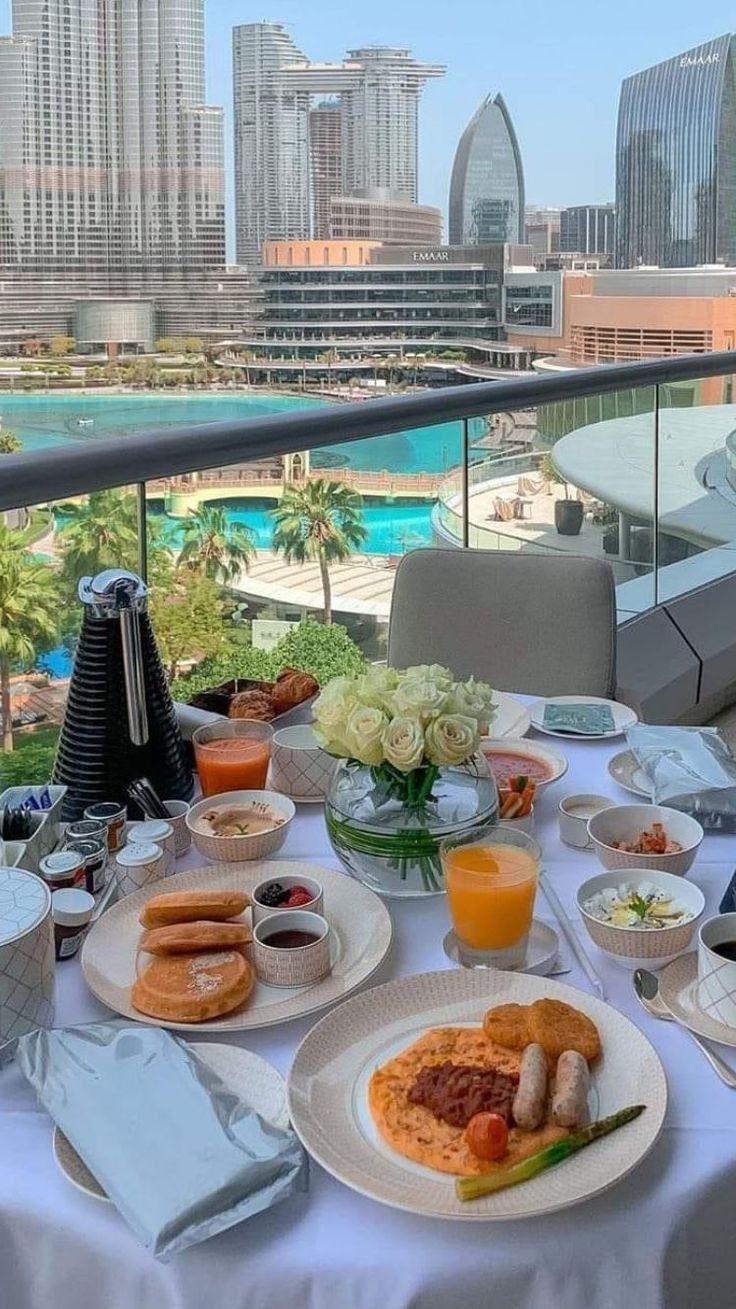 a table with food and drinks on it in front of a cityscape overlooking the ocean