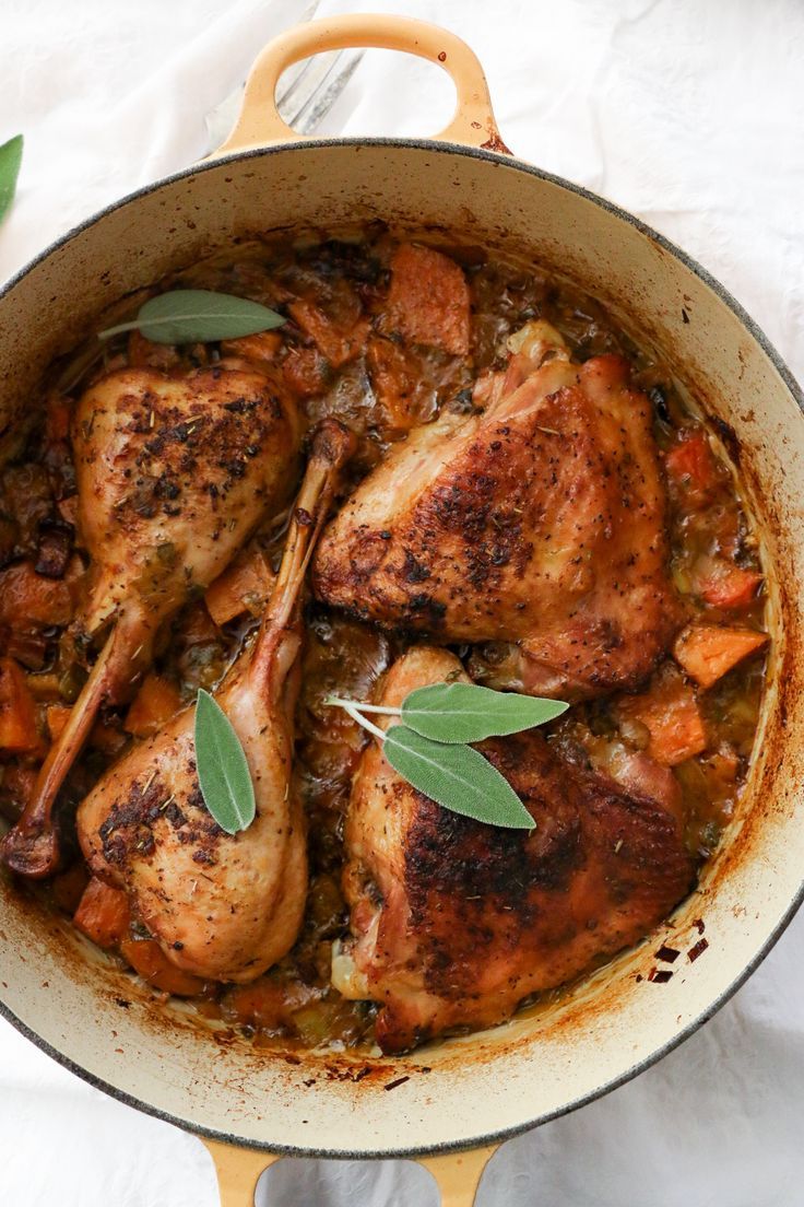 a pan filled with chicken and vegetables on top of a white cloth covered tablecloth