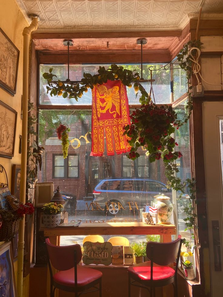 a window with plants hanging from it's sides and an old car in the background