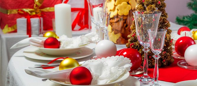 the table is set for christmas dinner with red and gold decorations