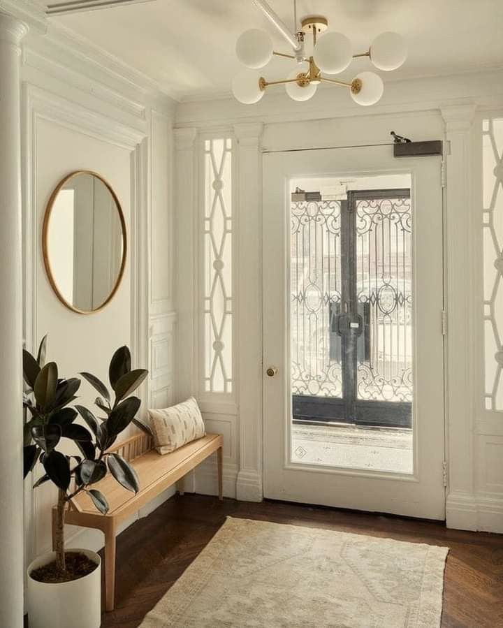 an entryway with a bench, mirror and potted plant in front of the door