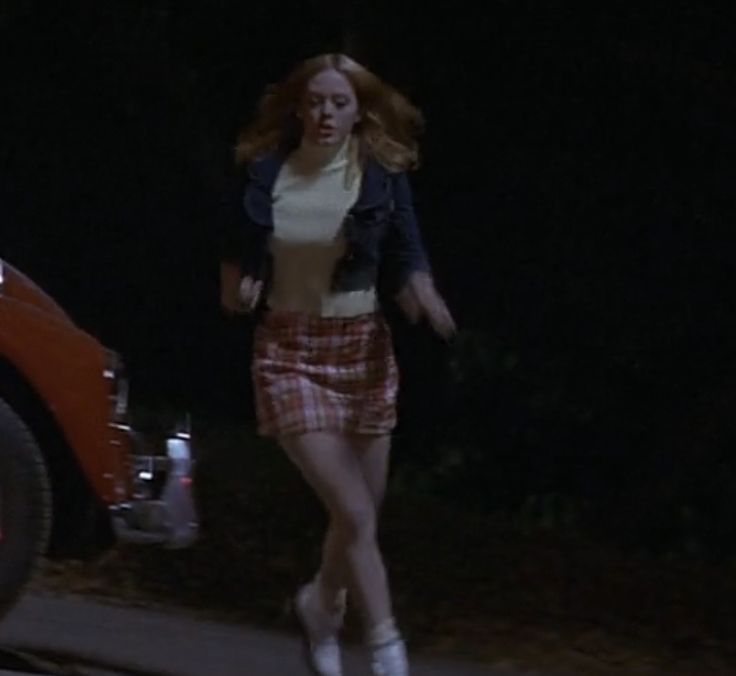 a woman is walking down the street at night with her hand on her hip while wearing plaid shorts