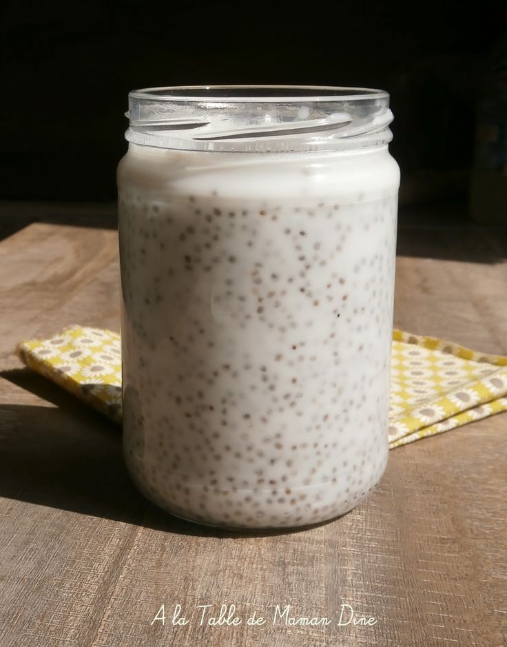 a glass jar filled with food sitting on top of a wooden table next to a yellow napkin