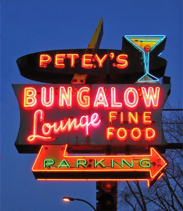 a neon sign that says bungalow lounge fine food and parking lot next to it