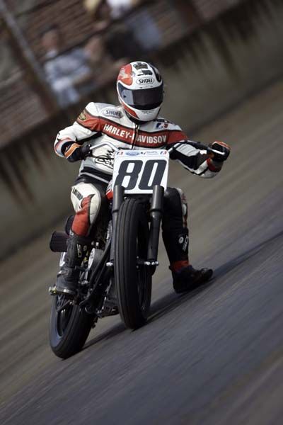 a man riding on the back of a motorcycle down a race track