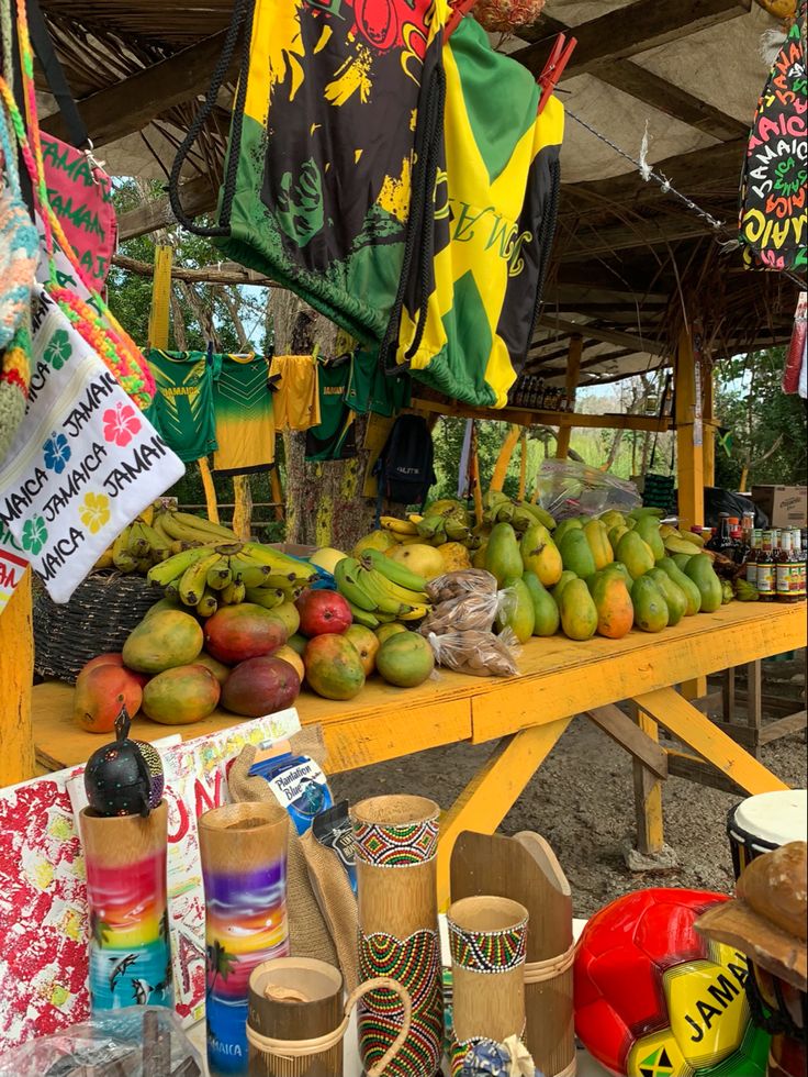 there are many fruits and vegetables on display at the market table with umbrellas in the background