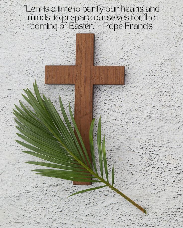 a wooden cross on the side of a building with a palm leaf in front of it