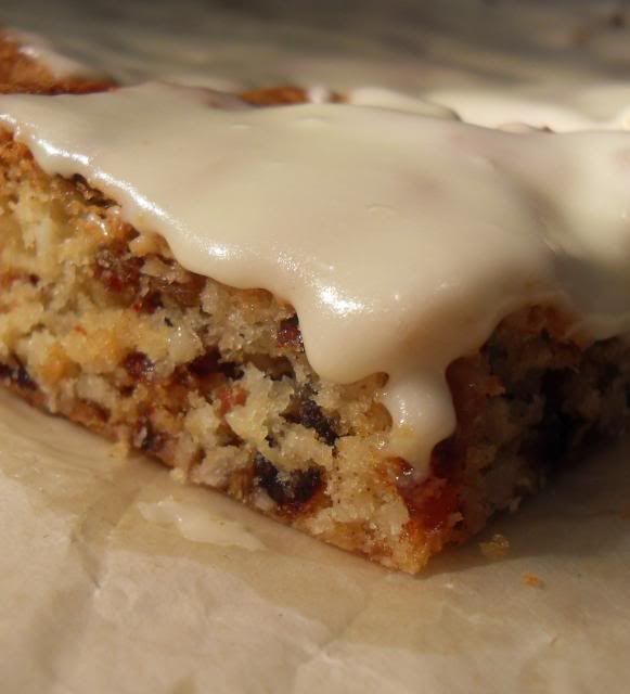 a piece of cake with icing on top of it sitting on some wax paper