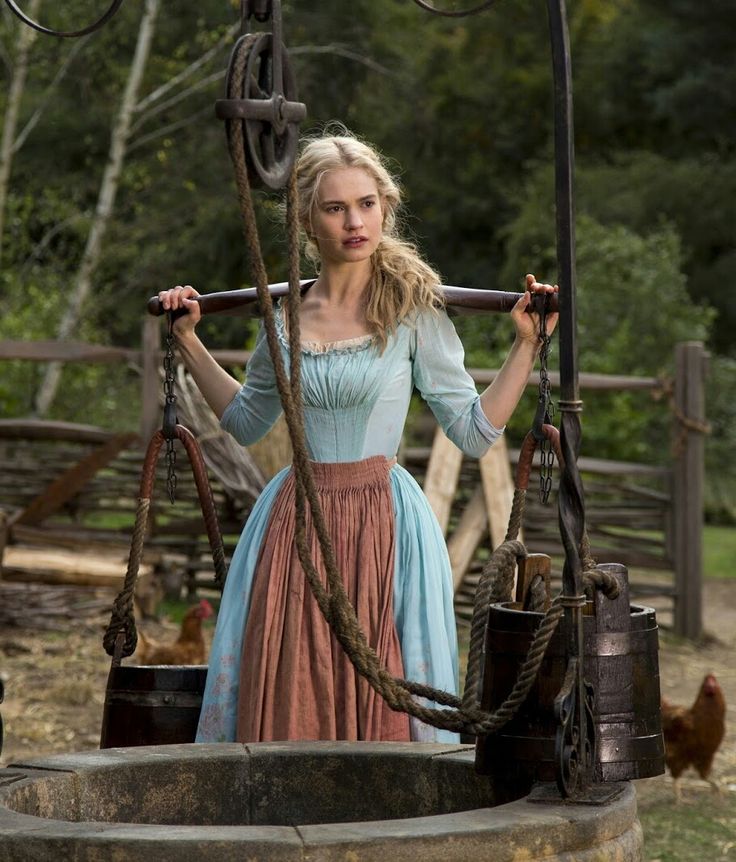 a woman standing on top of a swing in the middle of a field next to chickens