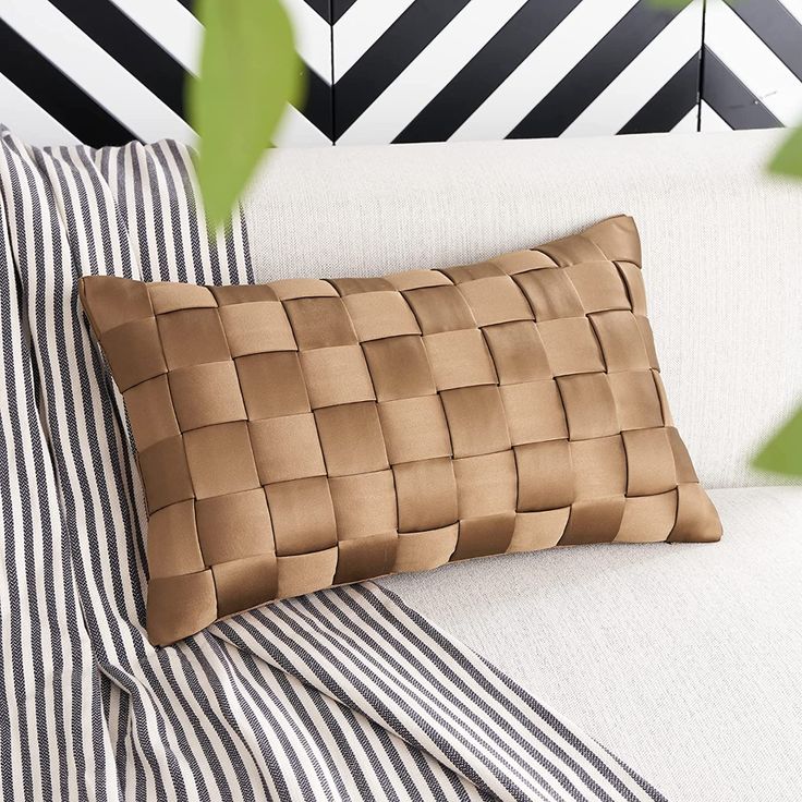 a close up of a pillow on a couch with black and white striped sheets in the background