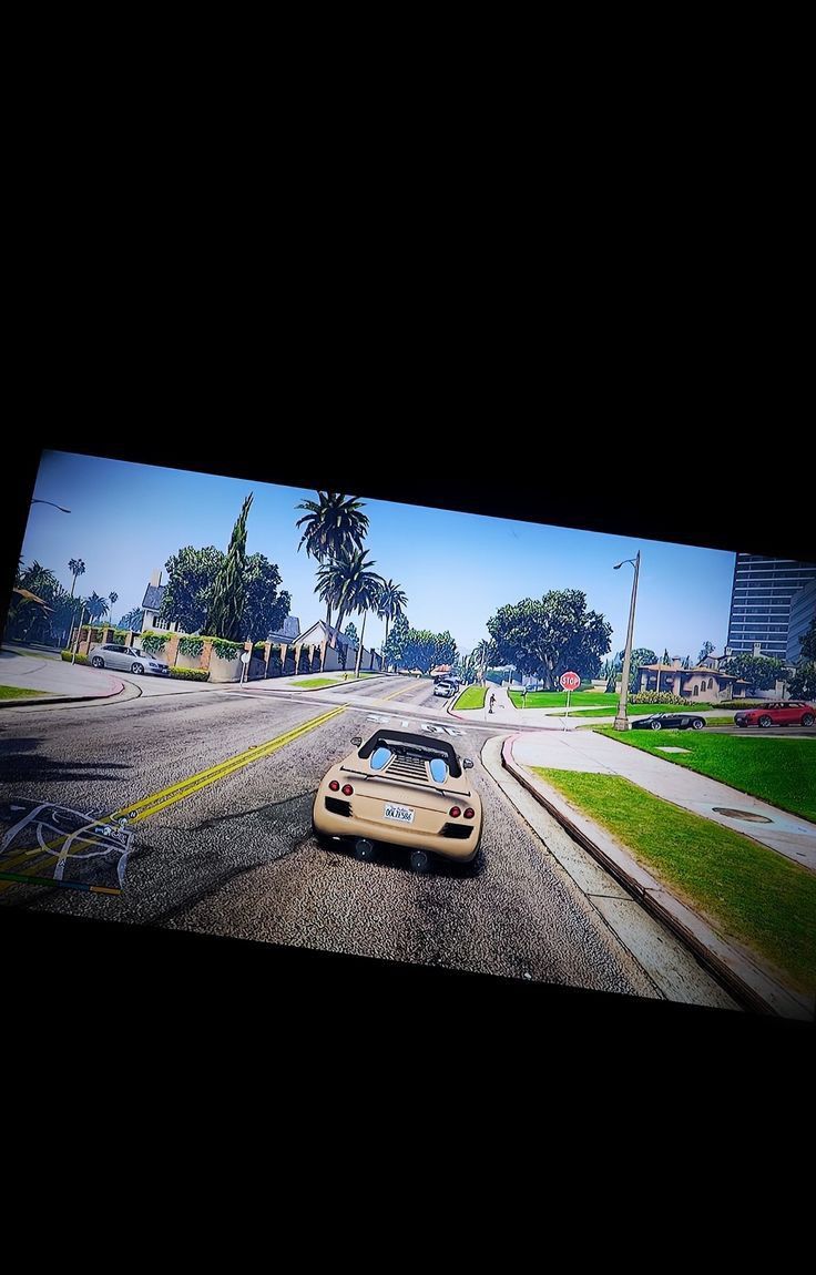 a car driving down a street next to tall buildings and palm trees in the background