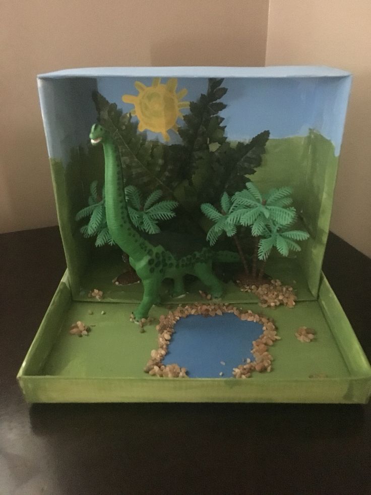 a dinosaur in a box with plants and rocks