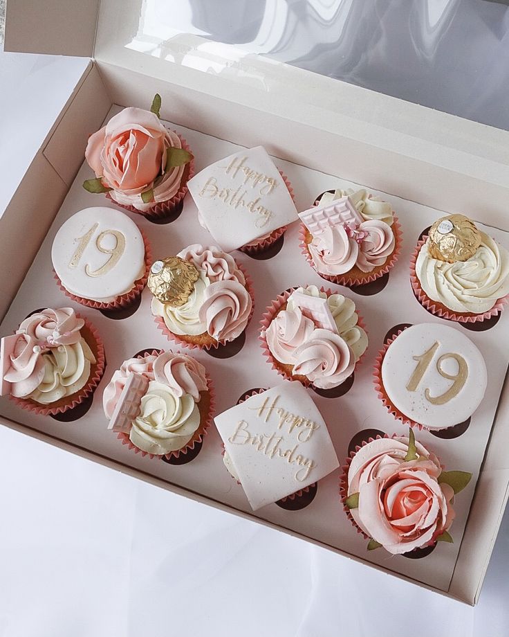 twelve cupcakes with pink frosting in a box