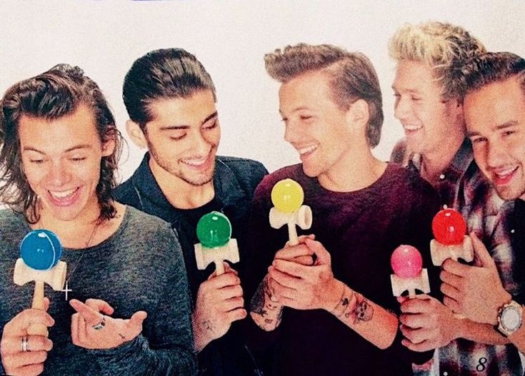 one direction are holding lollipops in their hands and smiling at the camera