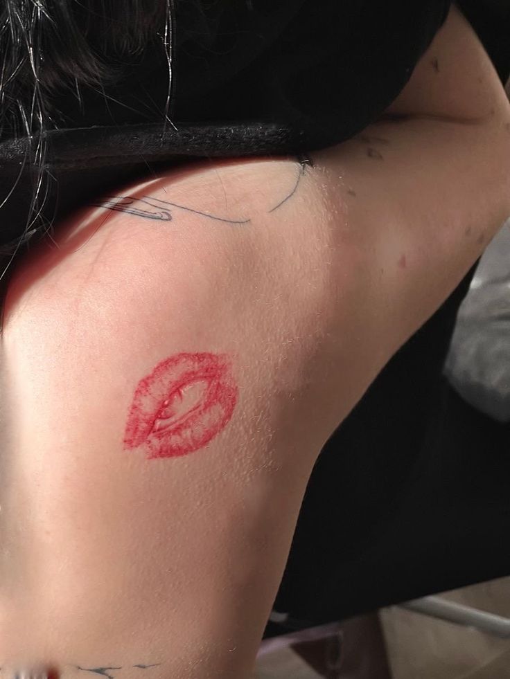 a woman with a red tattoo on her back and the word o painted on it