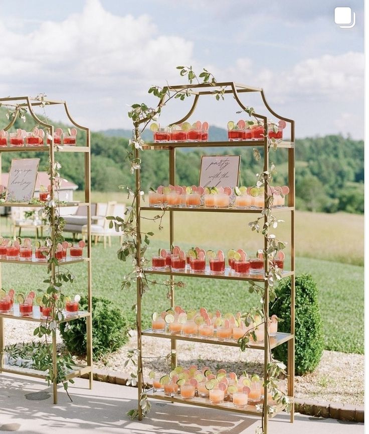 two tiered display stands with cupcakes on them in front of a grassy field