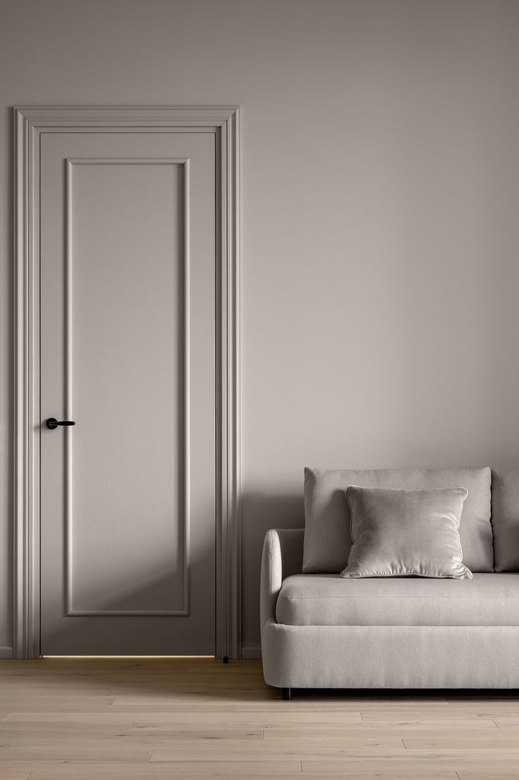 a white couch sitting in front of a door with pillows on it's back