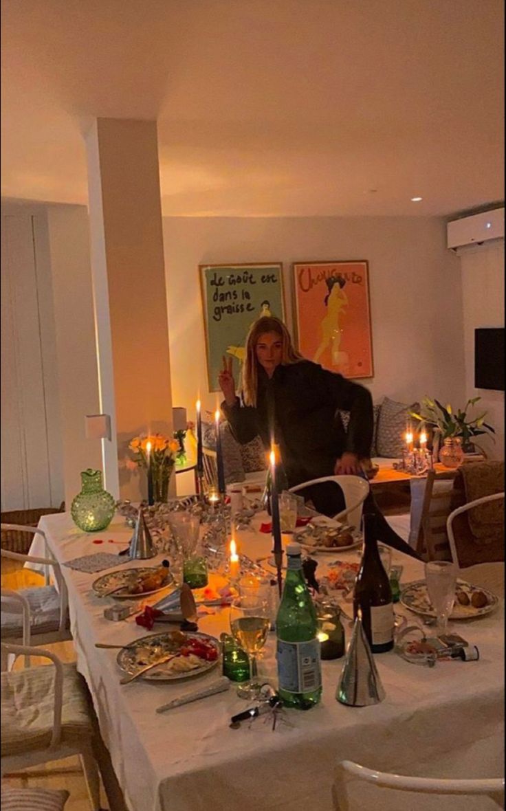 a woman sitting at a dinner table with candles on it