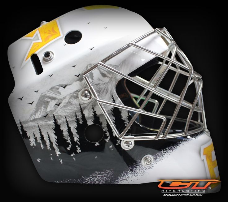 the goalie's helmet is covered in white and yellow paint with trees on it