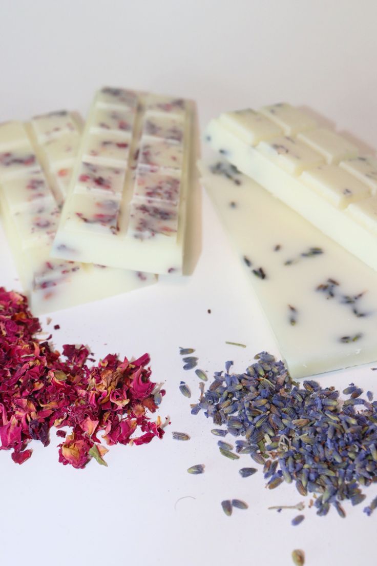 several different types of soaps and flowers on a white counter top with one bar of soap next to it