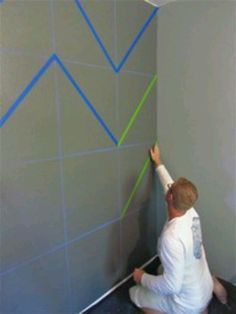 a man is painting the walls in his house with blue and green lines on it