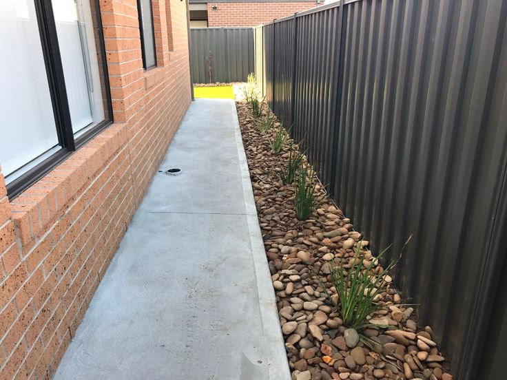 the side of a building with rocks and grass next to it