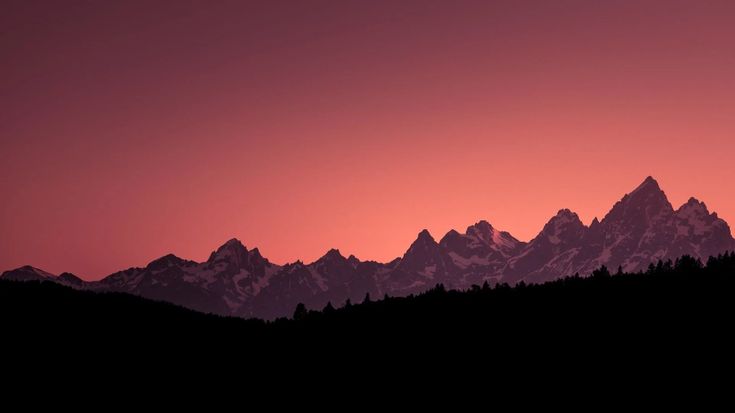 the mountains are silhouetted against an orange and pink sky