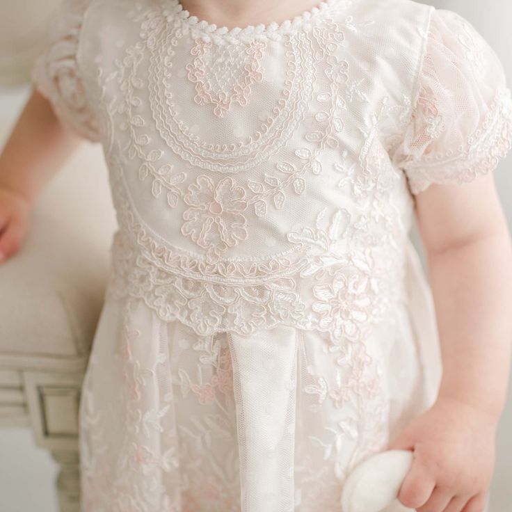 Handmade in the USA A gorgeous Baptism dress for your baby girl, our Elizabeth dress is handcrafted and expertly detailed. It is lined with rich silk Dupioni in an ivory color which enhances the gorgeous embroidered lace that falls over top. The soft pink and ivory embroidered Swiss Dot lace with cording is both comfortable and elegant, and will have everyone believing this is a handmade family dress passed down specially for your little one. Our vintage pink champagne Dupioni silk sash ties all Cream Pearl Embroidery Dress For Ceremony, Lace Dress With Pearl Embroidery For Ceremony, Ceremony Lace Dresses With Pearl Embroidery, Elegant Fitted Pink Baptism Dress, Fitted Pearl Embroidered Dress For Baptism, Elegant First Communion Dress With Pearl Embroidery, Lace Baptism Dress With Floral Embroidery, White Floral Embroidered Baptism Dress, Elegant Cream Lace First Communion Dress