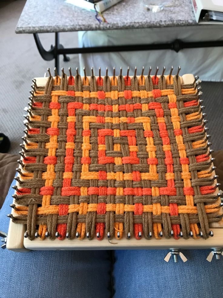 someone is sitting in front of a table with an orange and brown weaving pattern on it