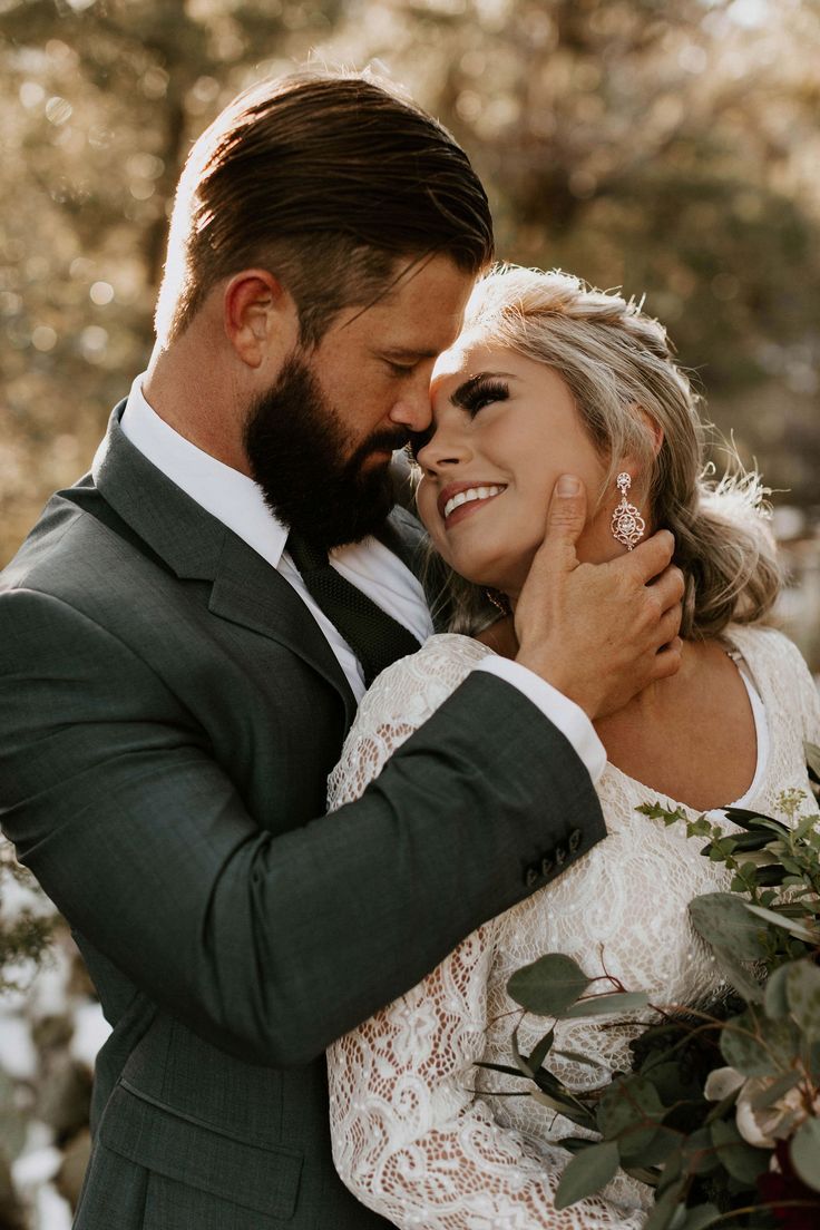 a bride and groom embracing each other in front of trees