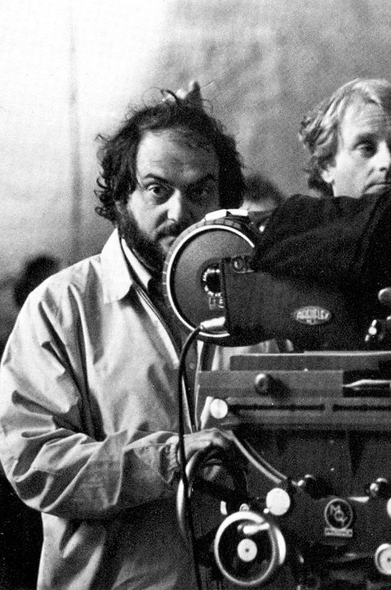 black and white photograph of two men looking at an old movie projector with one man holding the camera