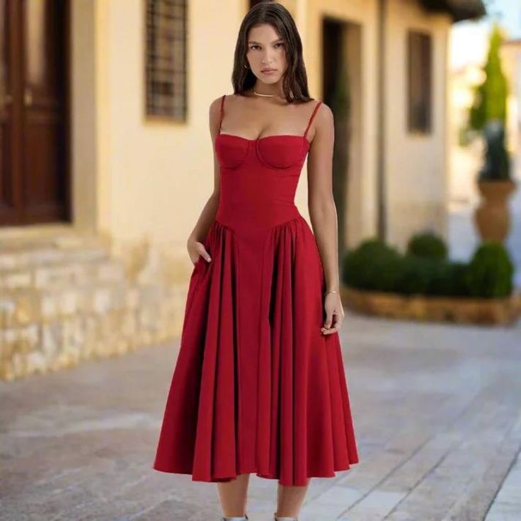 a woman in a red dress is standing outside